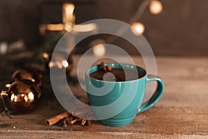 Cup of hot cocoa or hot chocolate on knitted background with fir tree and snow effect, traditional beverage for winter