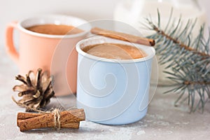 Cup of hot cocoa or hot chocolate on stone background with cinnamon sticks. Traditional beverage for winter time, vintage toning.