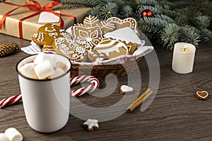 A cup of hot cocoa with marshmallows and gingerbread cookies on a wooden table. Christmas decor. Focus on the