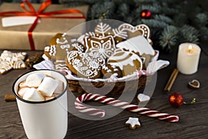 A cup of hot cocoa with marshmallows and gingerbread cookies on a wooden table. Christmas decor. Focus on the cup.