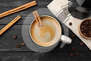 Cup of hot coffee with aromatic cinnamon on black wooden table, flat lay