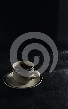 a cup of hot coffee on a black background. dark scene. banner space mock-up for adding text