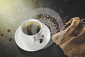 cup of hot coffee and coffee beans in a sack on