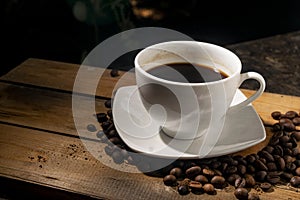 A cup of hot coffee with coffee beans  on wooden board