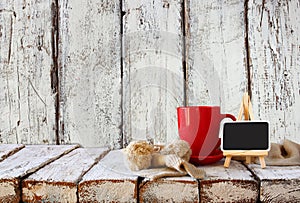 Cup of hot coffee and cozy knitted scarf and blackboard