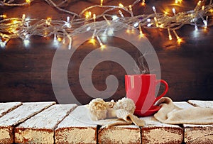 Cup of hot coffee and cozy knitted scarf on wooden table