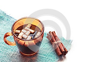 Cup of hot coffee with marshmallows and cinnamon on white background.