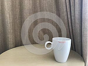 Cup of hot coffee with red lipstick mark on wood table