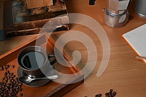 Cup of hot coffee and roasted coffee beans on wooden table.