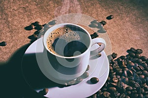 Cup of hot coffee and saucer on a brown table. Dark background.