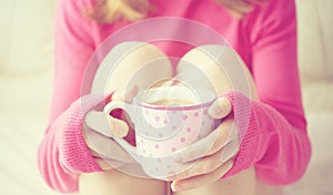 Cup of hot coffee warming in the hands of a girl