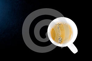 A cup of hot coffee in white mug on black background
