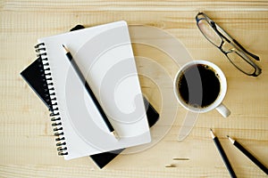 Cup of hot coffee  on wooden background with notebook.  Work from home concept