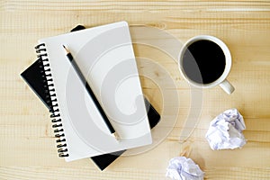 Cup of hot coffee  on wooden background with notebook.  Work from home concept