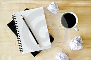 Cup of hot coffee  on wooden background with notebook.  Work from home concept