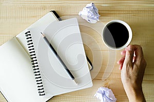 Cup of hot coffee  on wooden background with notebook.  Work from home concept