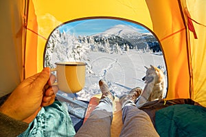 Cup of hot drink in the hand and wonderful view of snowy mountain tops through the open entrance of the tent. The beauty of a