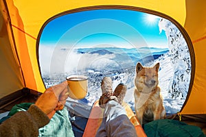 Cup of hot drink in the hand and wonderful view of snowy mountain tops through the open entrance to the tent. The beauty of a