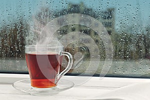 Cup of hot drink near window on day