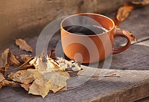 Cup with hot drink on a wooden background autumn