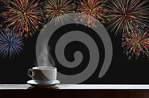 Cup of hot drinks on wooden desk with new year celebrate fireworks on night sky