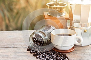 A cup of hot espresso coffee mugs and roasted coffee beans with moka pot placed on wooden floor background,coffee morning,