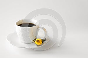 A cup of hot fresh black coffee with foam on a white background. Coffee cup on a round saucer centered inside the frame. Top view