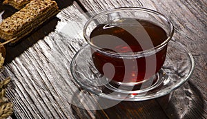 A cup of hot herbal tea and cookies on the old wooden background