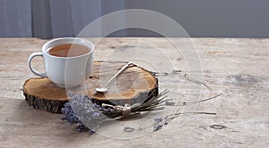 A cup of hot herbal tea and lavender on an old wooden background.