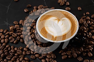 Cup of hot latte coffee with beautiful milk foam latte art texture with coffee bean on black marble background. Overhead