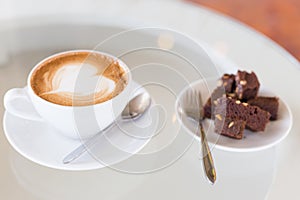 A cup of hot Latte coffee on old wooden table with brownie cake