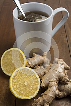 Cup of hot lemon ginger tea with tea bag isolated on wood background