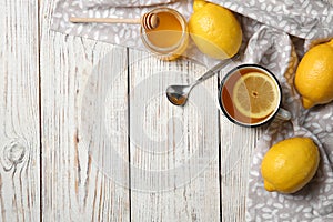Cup with hot lemon tea and honey on wooden background, top view