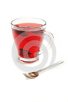 Cup with hot red carcade floral tea and teaspoon photo