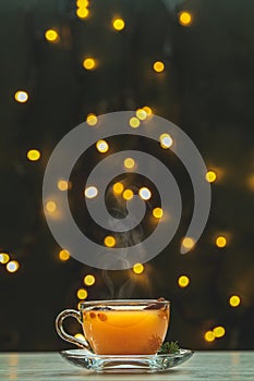 Cup of hot spicy tea with yellow orange barries on dark Christmas and New Year background with light bokeh. Beautiful holiday