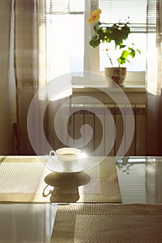 cup of hot steaming coffee on a sunny morning on the kitchen table