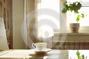 cup of hot steaming coffee on a sunny morning on the kitchen table