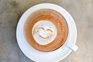 Cup of hot tasty cappucino with smile as art latte