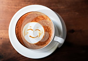 Cup of hot tasty cappucino with smile as art latte