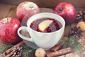 Cup of hot tea with apple and berries Christmas winter beverage Christmas food concept Wooden background Cinnamone sticks Apples T photo