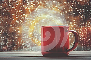 A cup of hot tea in the background rain outside the window.