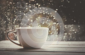 A cup of hot tea in the background rain outside the window.