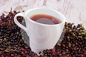 Cup of hot tea with elderberry juice and heap of berry