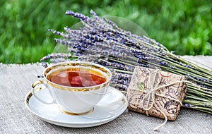 Cup of hot tea, fragrant lavender and gift. Summer tea in the garden.