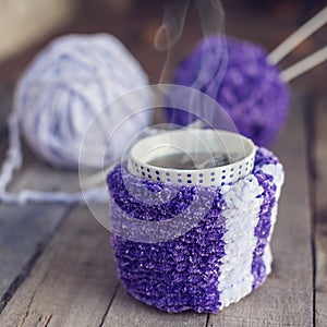 Cup of hot tea in knitted scarf