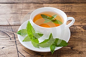 Cup of hot tea with mint and brown sugar on a wooden table