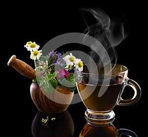 Cup of hot tea and mortar with herbs