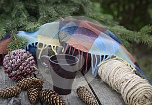 Cup of hot tea on a rustic wooden table with decor of cones, packthread, fir branches. Preparing for Christmas.