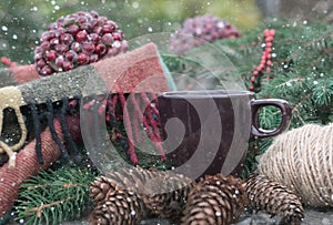 Cup of hot tea on a rustic wooden table. Still life of cones, twine, patskthread, fir branches. Drawn snow.