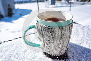 A cup of hot tea on the snowy garden terrace at winter